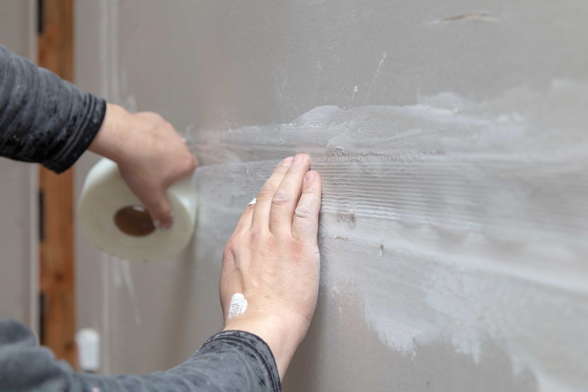 Una persona aplicando malla de fibra en la pared.
