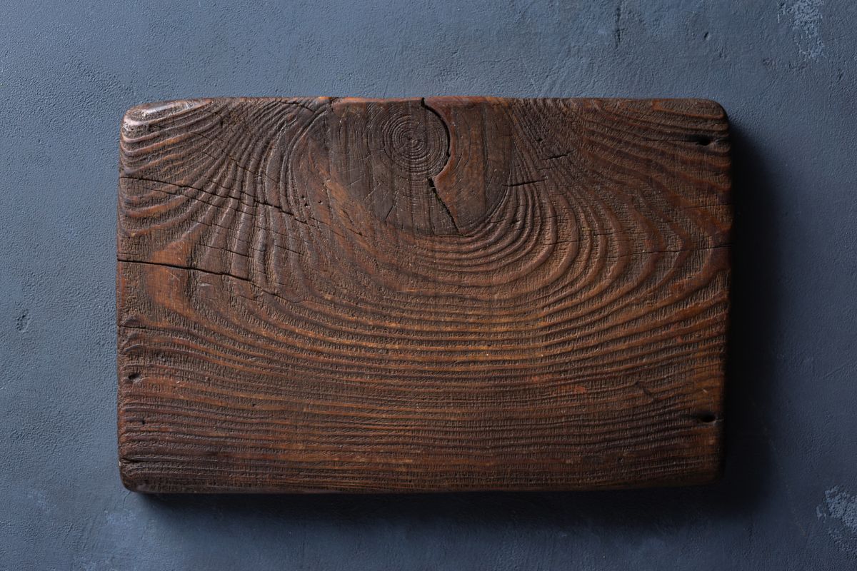Una vieja tabla de cortar de madera sobre un fondo de piedra.