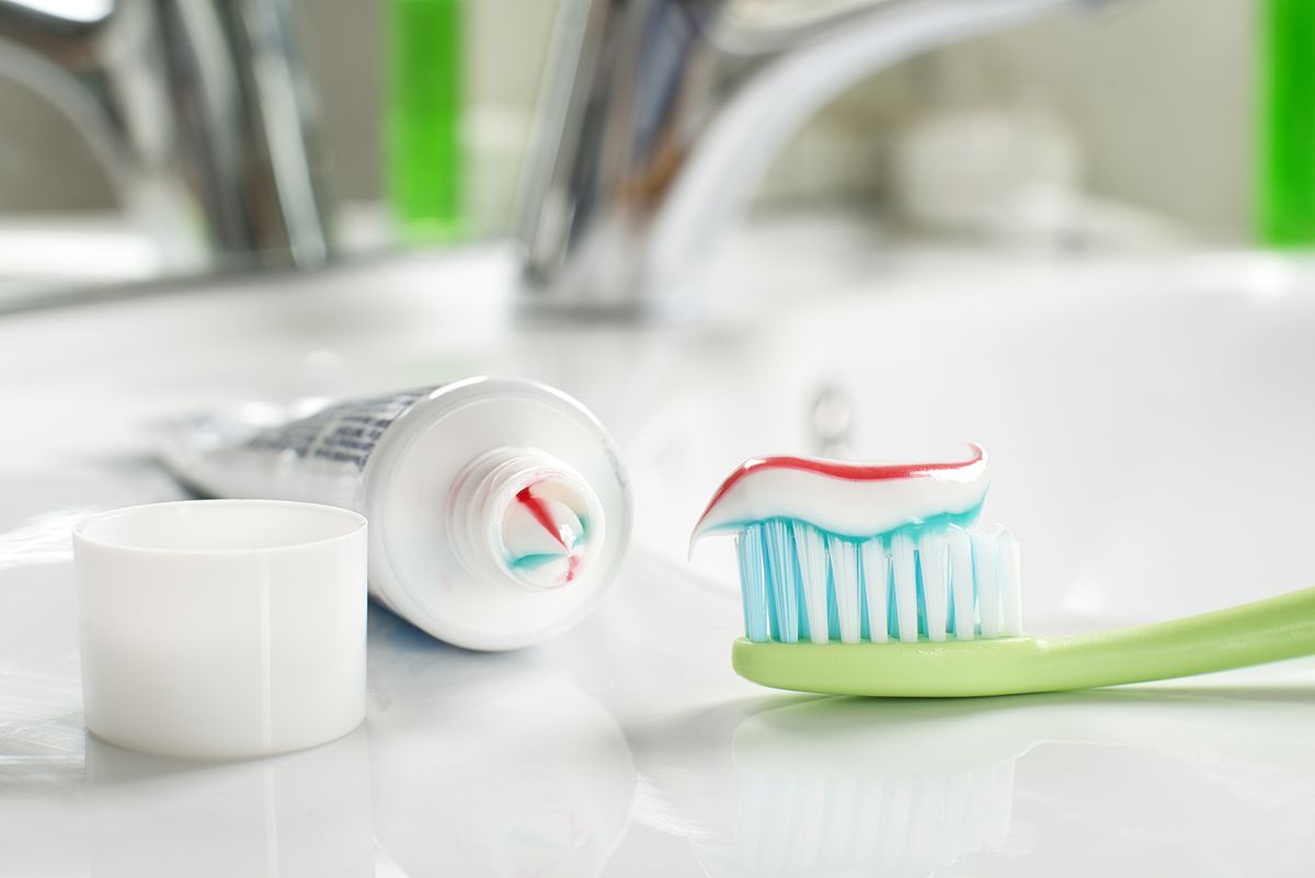Cepillo de dientes con pasta dentífrica en un cuarto de baño, plano cerrado.