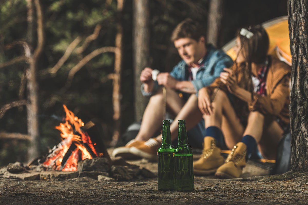 Una pareja en una acampada frente a una hoguera.