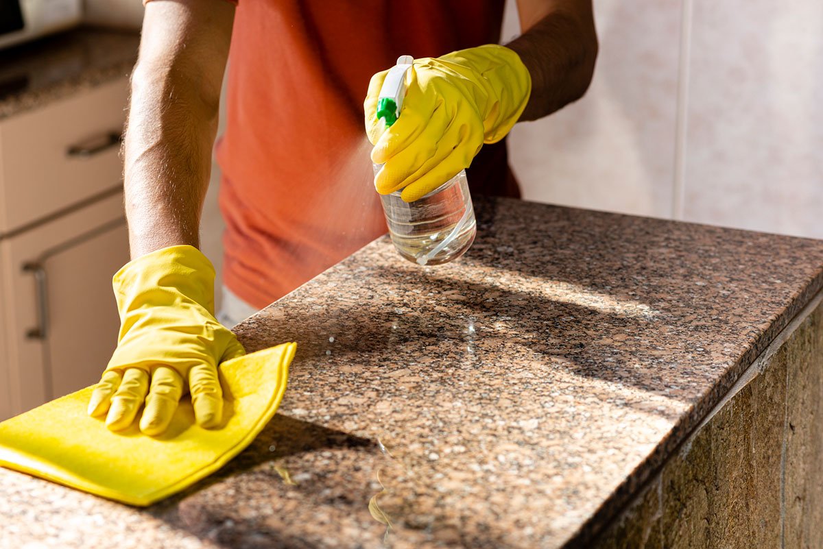 Una persona con guantes limpiando un granito.