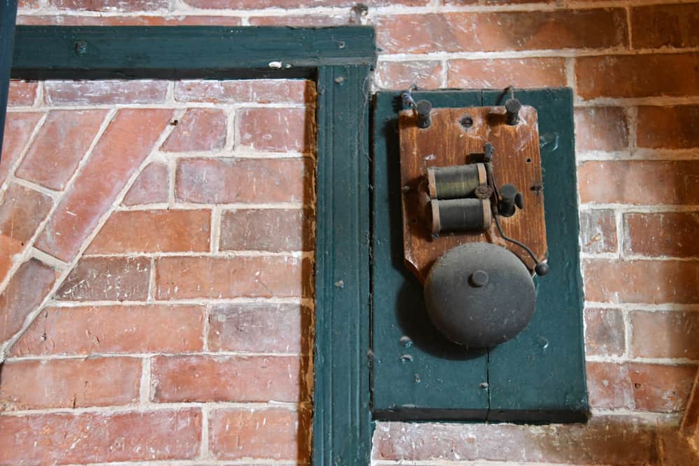 Este es un vistazo a una alarma doméstica antigua montada en una pared de ladrillo.