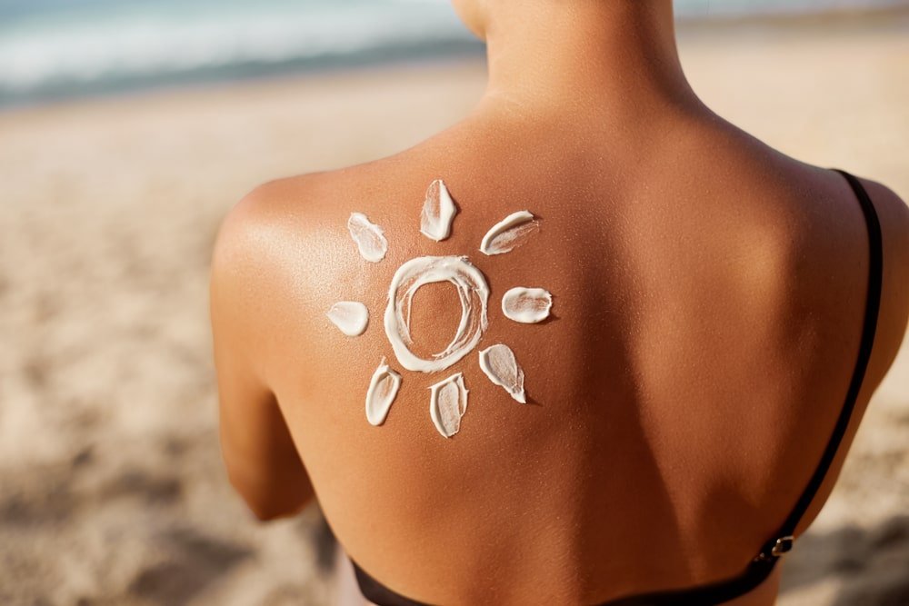 Aplicación de protector solar en la espalda de una mujer.
