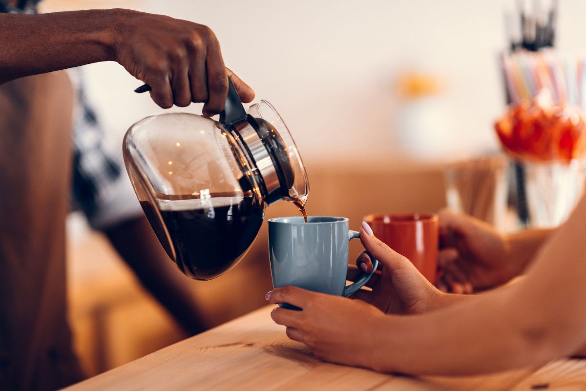 Barista vertiendo café de la cafetera en una taza azul
