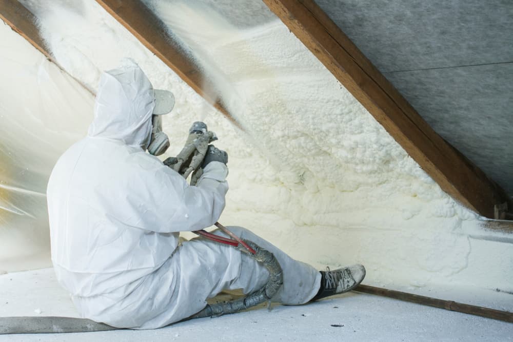 Un técnico aplicando aislamiento de espuma en spray en el ático.