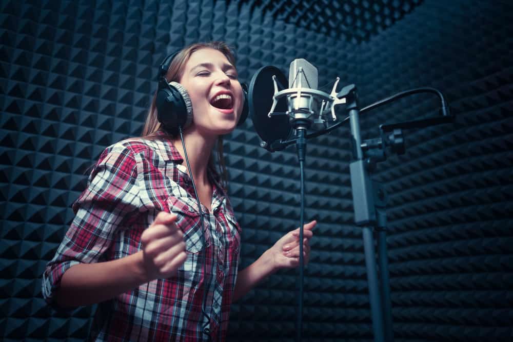 Esta es una imagen de cerca de una mujer cantando dentro de un estudio de grabación con insonorización.