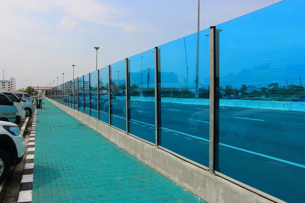 Esta es una vista cercana de una autopista con barreras acústicas laterales hechas de vidrio insonorizado.