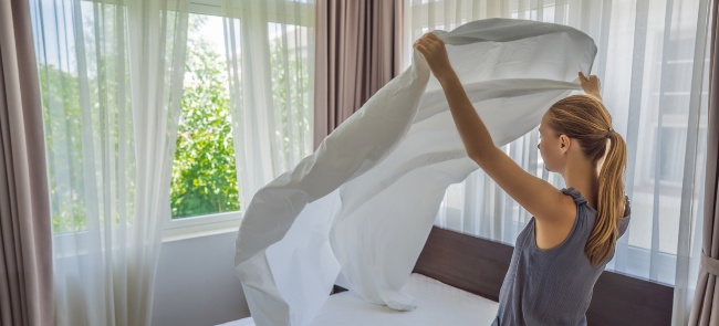 Mujer joven cambiando las sábanas de la cama