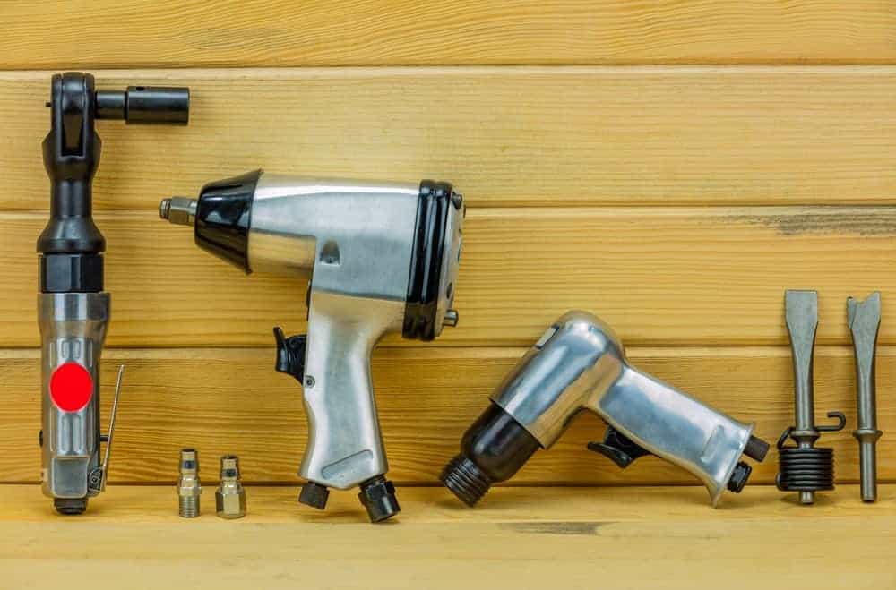 Diferentes tipos de herramientas neumáticas sobre fondo de madera.