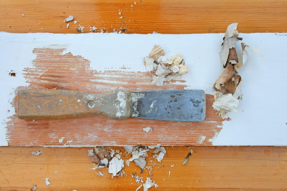 Rascador de pintura sobre superficie de madera utilizado para eliminar la pintura vieja.