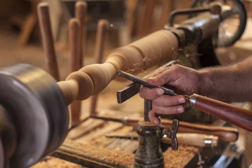 Un carpintero utiliza un torno para dar forma a una pieza de madera.