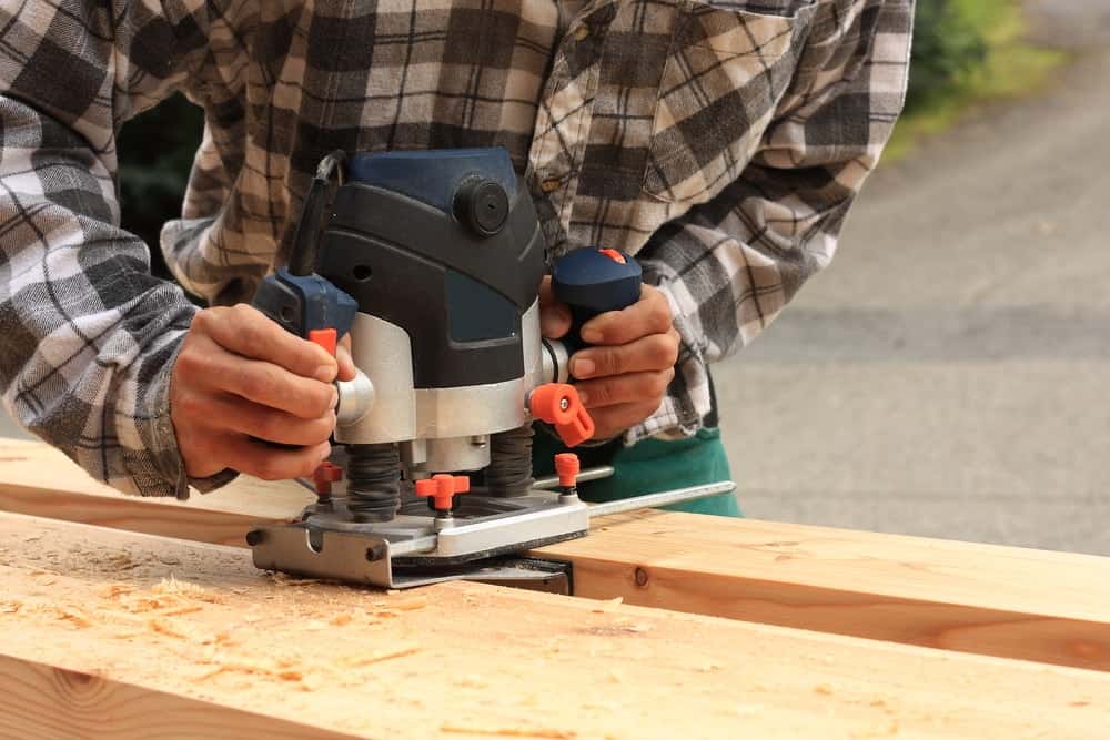 Un carpintero experto utiliza una fresadora eléctrica para cortar piezas de madera.