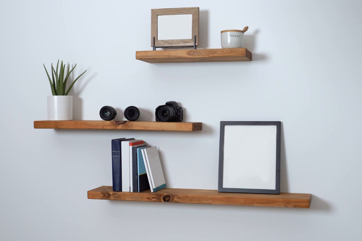 Una estantería flotante de madera con libros y un cuadro es minimalista.