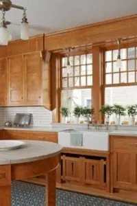 Los elementos de madera dominan una cocina Craftsman renovada, acentuados por la encimera blanca de la isla de cocina circular y una península en forma de U.