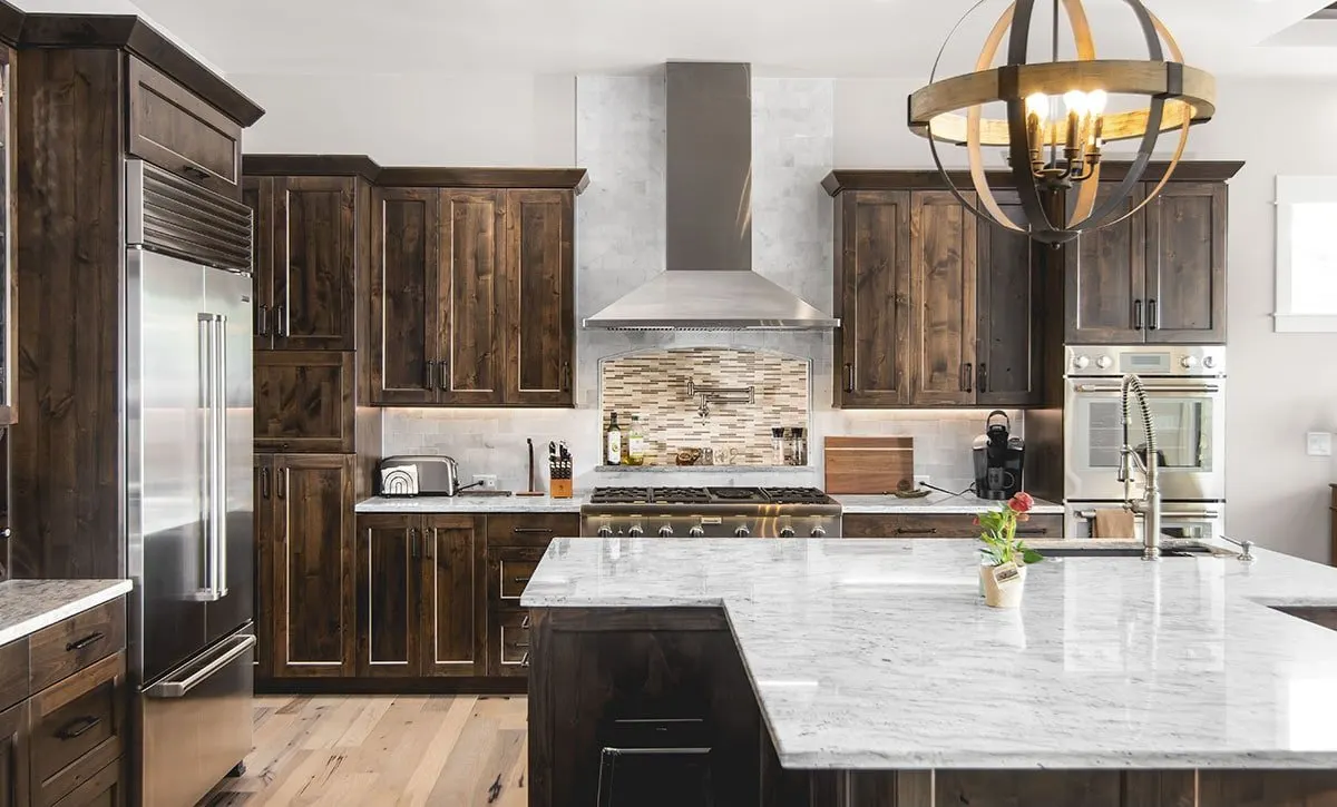 Esta cocina artesanal está llena de elementos de madera maciza. Contrasta maravillosamente con las encimeras de mármol blanco y el salpicadero.