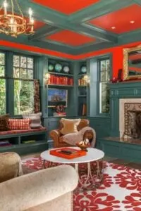 El diseño del techo artesonado enlaza con una acogedora guarida de paredes verdes con detalles rojos. Hay una gran chimenea y un banco para sentarse.
