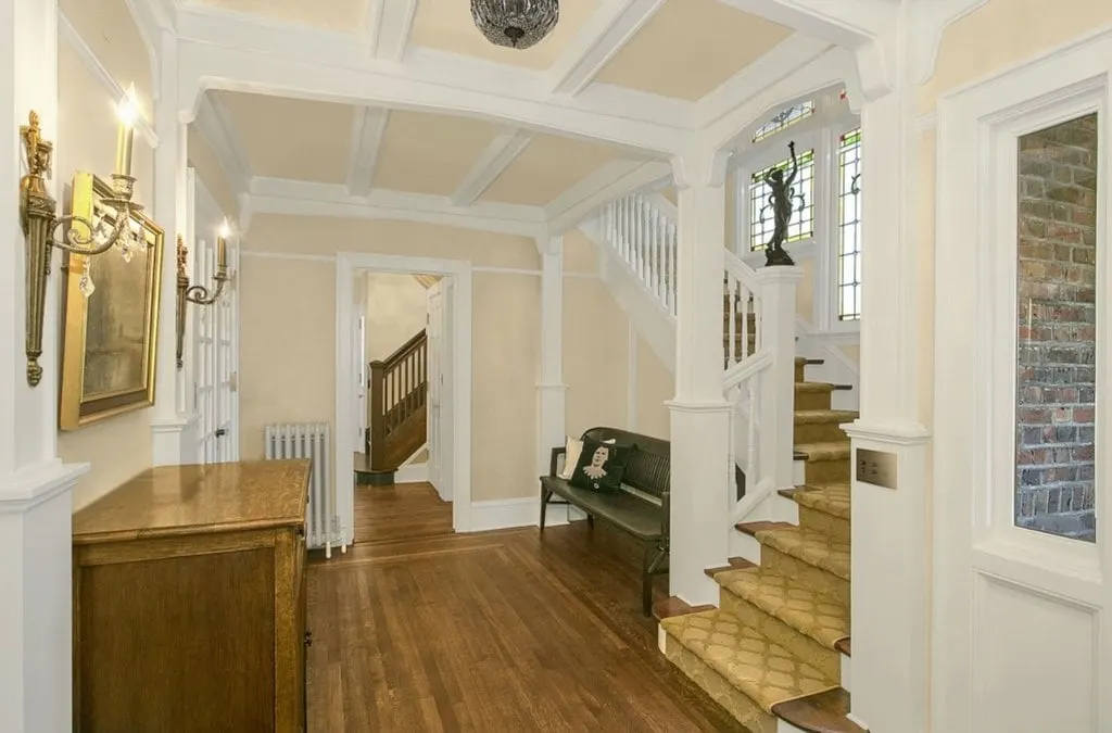 Esta entrada de casa presenta suelo de madera y paredes de color beige junto con un techo artesonado.