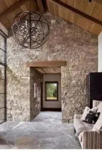 Los impresionantes suelos asimétricos de pizarra y las paredes de piedra beige, junto con los elementos de madera, se combinan para crear una preciosa entrada de montaña.