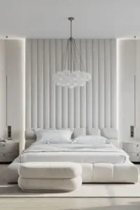 Una pared de cama con mechón de canal es la protagonista de este lujoso dormitorio de estilo nouveau. La cama de plataforma de canal blanco se coloca sobre una alfombra de textura marfil para crear calidez.