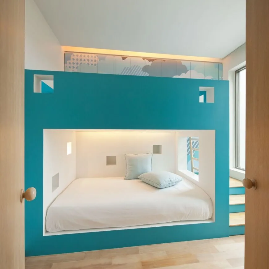 Una habitación infantil con una cama a medida. La habitación tiene suelo de madera y una ventana corredera de cristal.