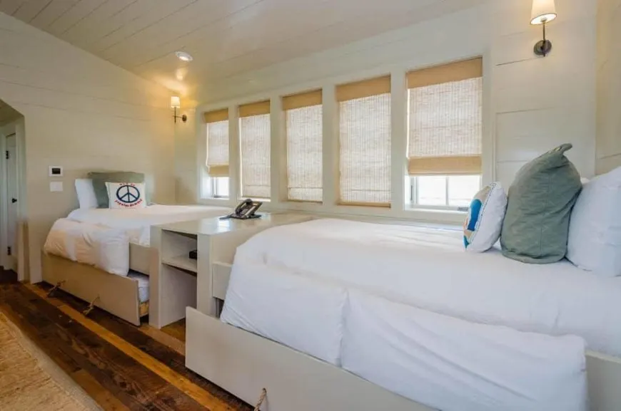 Un vistazo más de cerca a las camas a medida de este dormitorio infantil. La habitación presenta suelos de madera y paredes de madera, junto con un techo de cobertizo blanco.