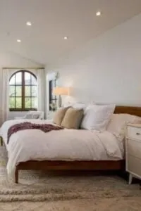 Espacioso dormitorio principal en Pacific Palisades con suelo de madera noble rematado por una enorme alfombra.