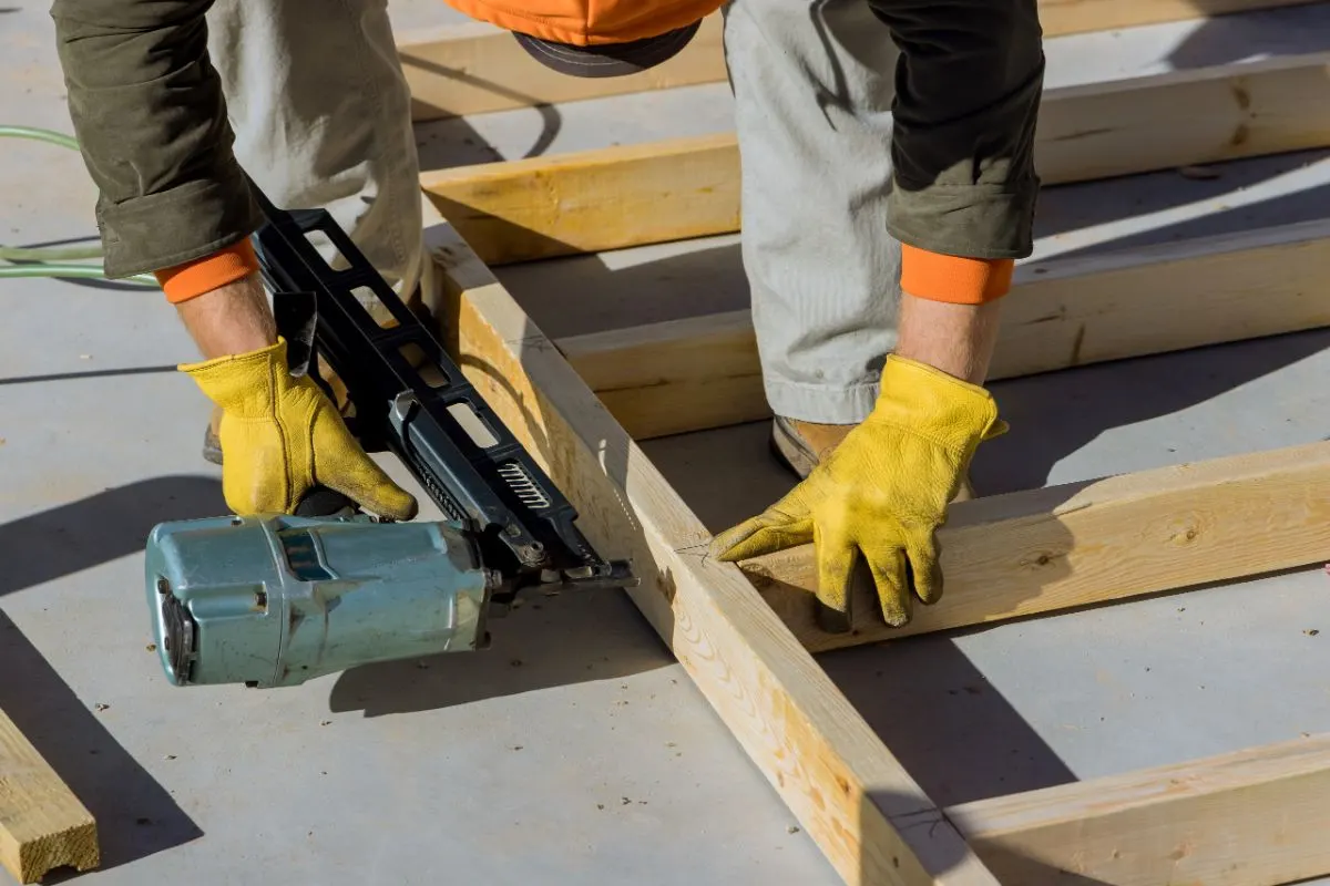 Un hombre utiliza un martillo neumático para fabricar marcos de madera.