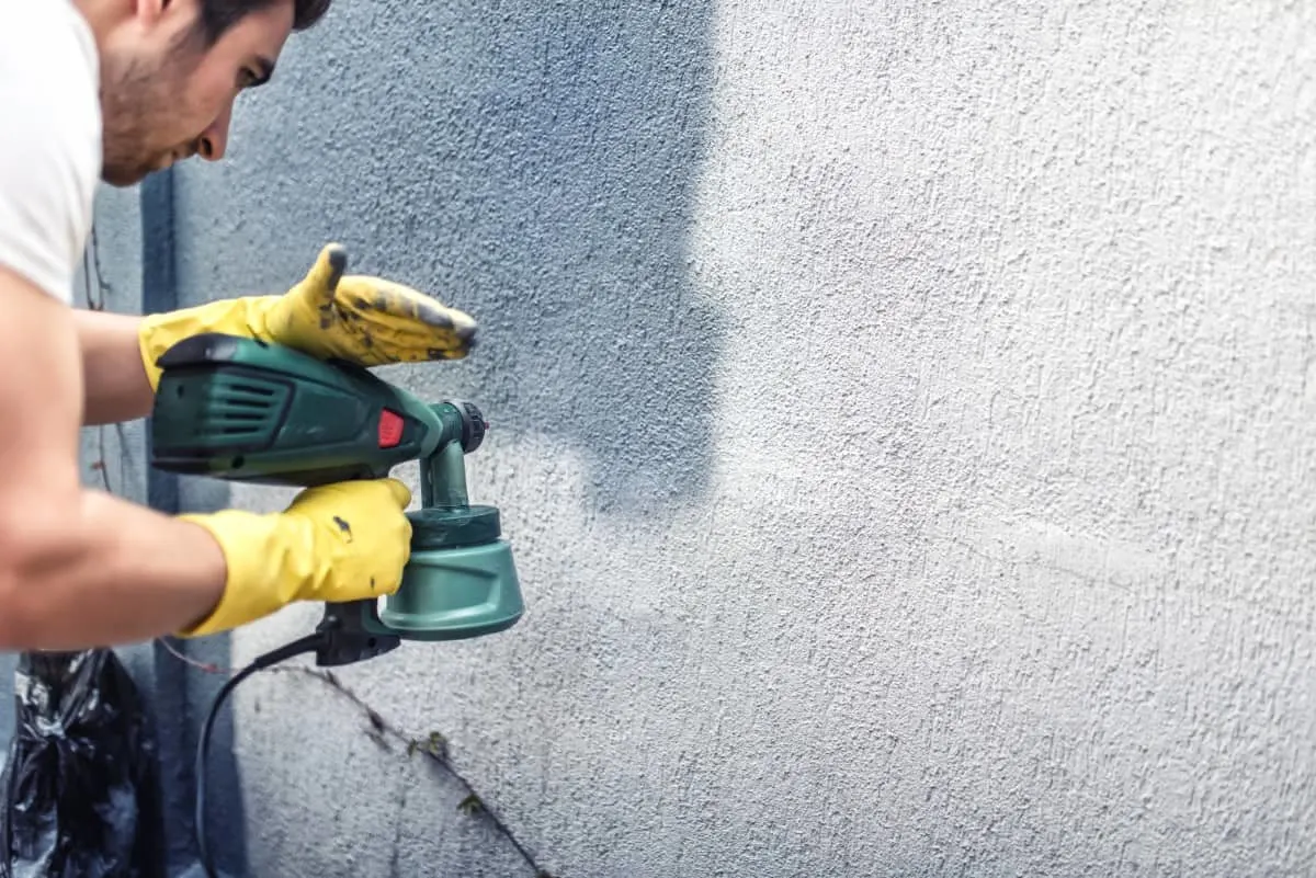 Hombre pintando con spray una pared de hormigón.