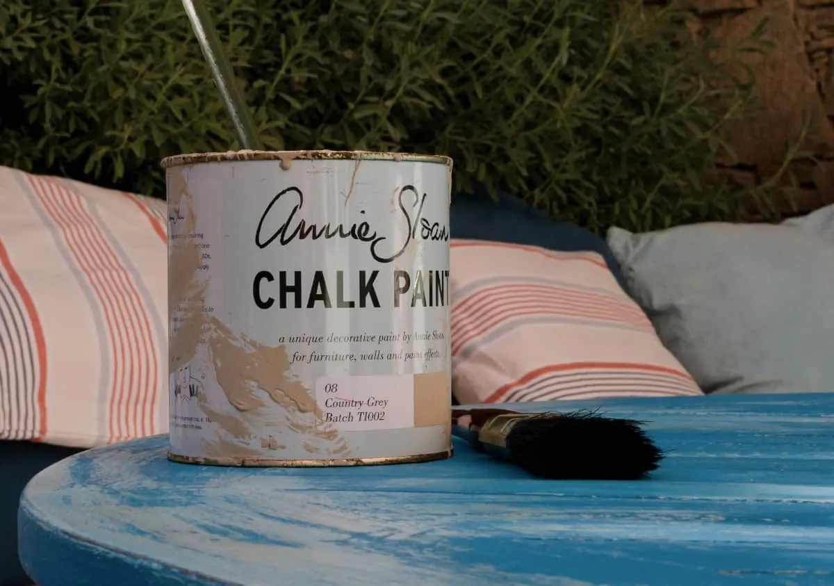 Una lata de pintura a la tiza Annie Sloan sobre una mesa azul desgastada.
