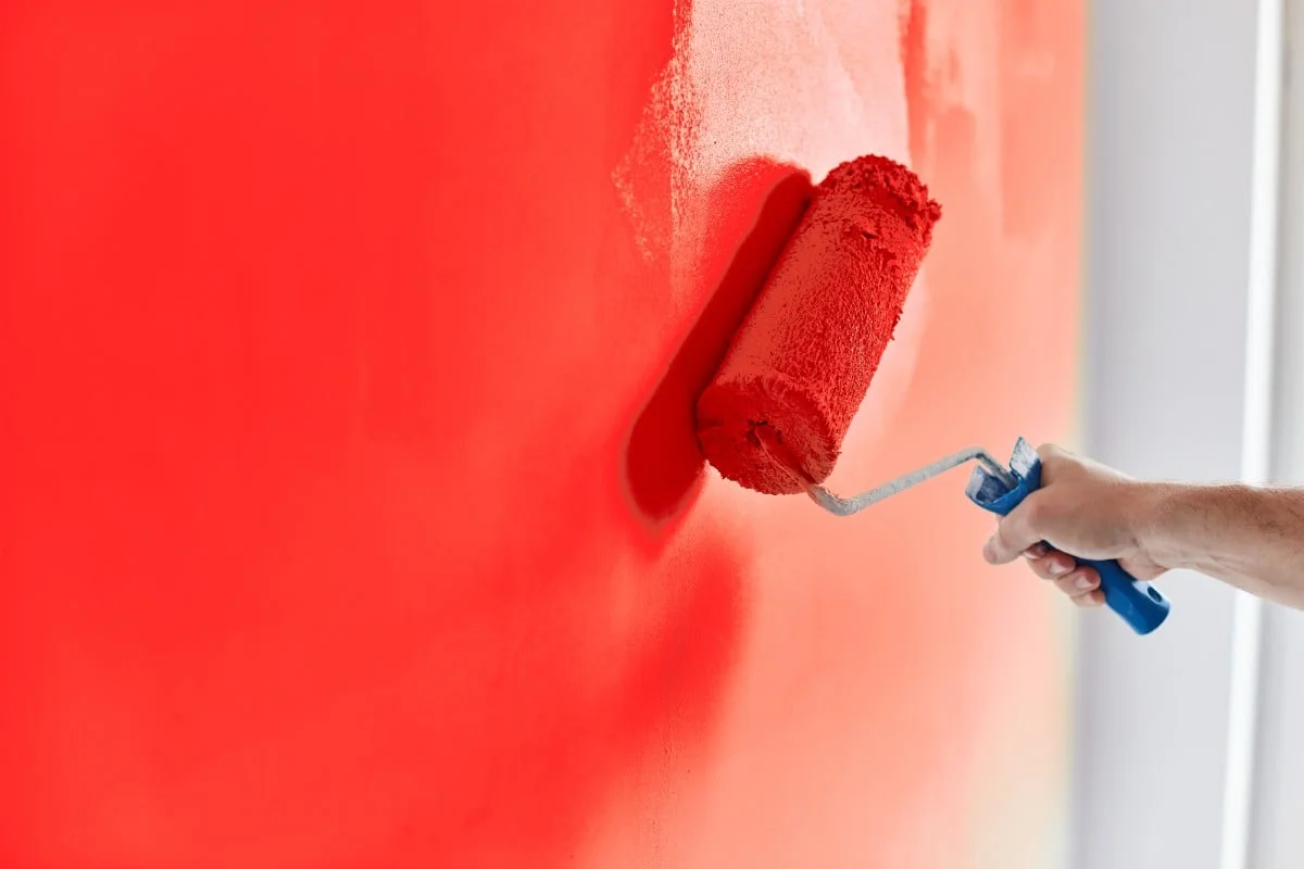 Hombre pintando a mano la pared con brocha de rodillo.