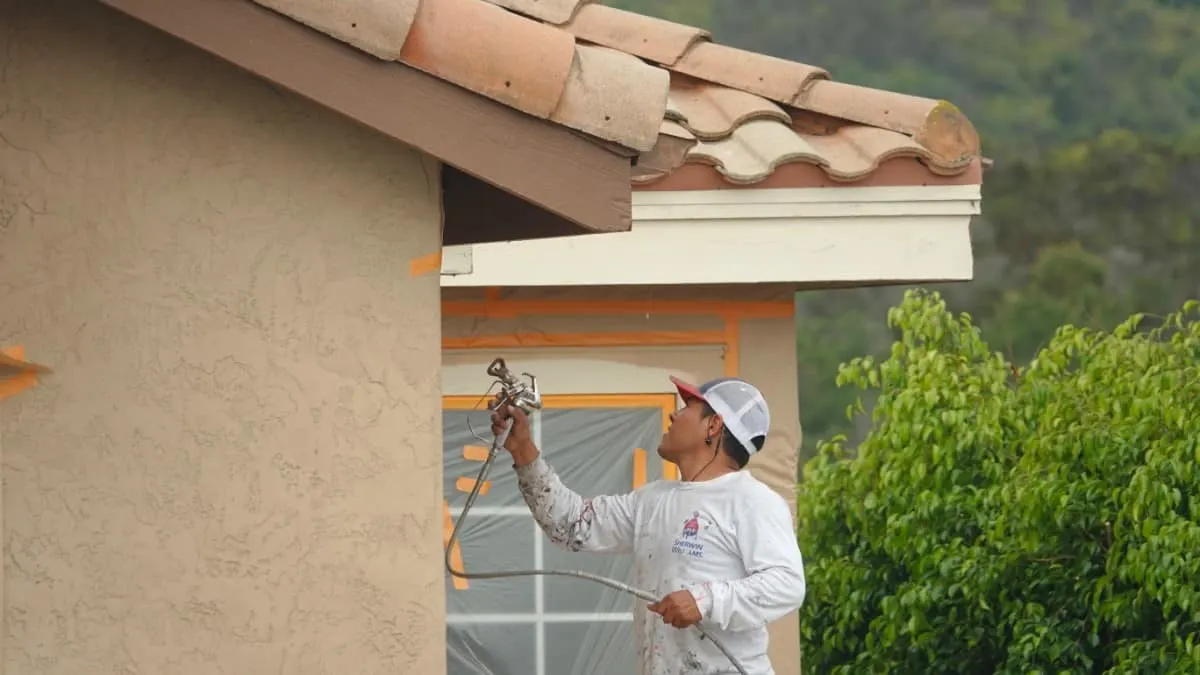Hombre pintando el exterior de la casa con una pistola de pintura.