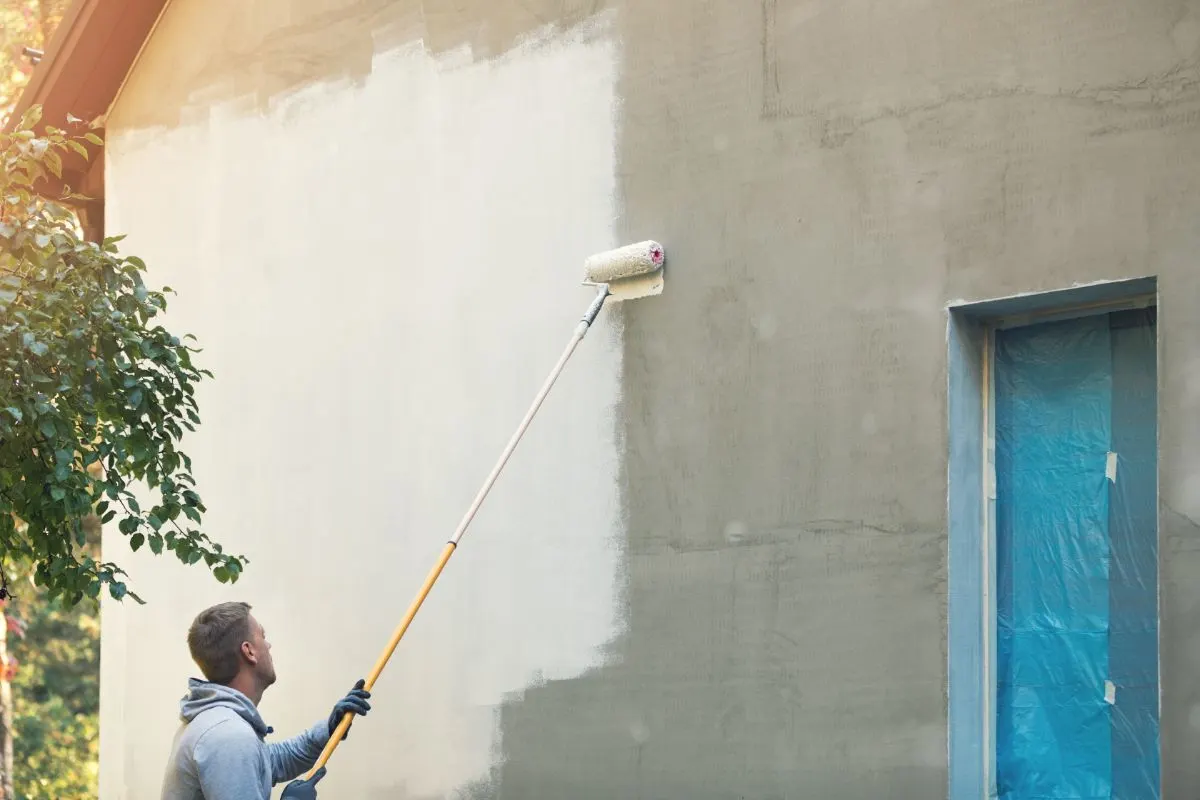 Un hombre pinta las paredes de una casa utilizando un rodillo de pintura.
