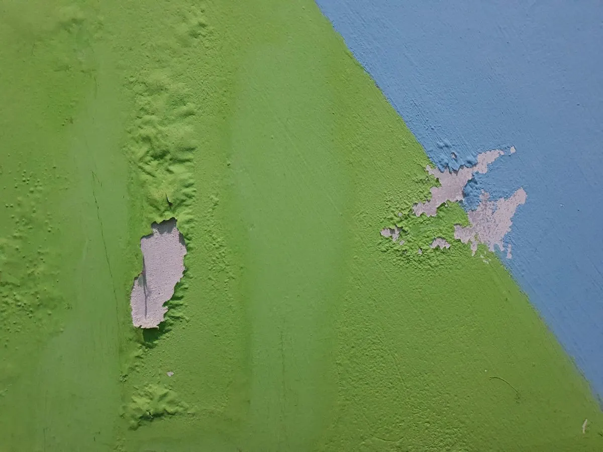 Una pared con daños por burbujas de pintura.
