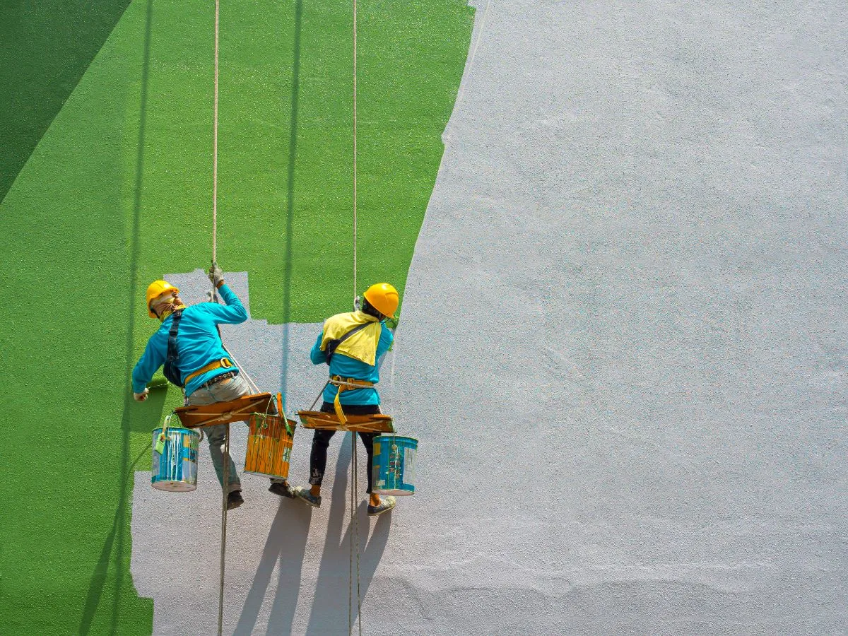 Obreros pintando en las paredes de un edificio.