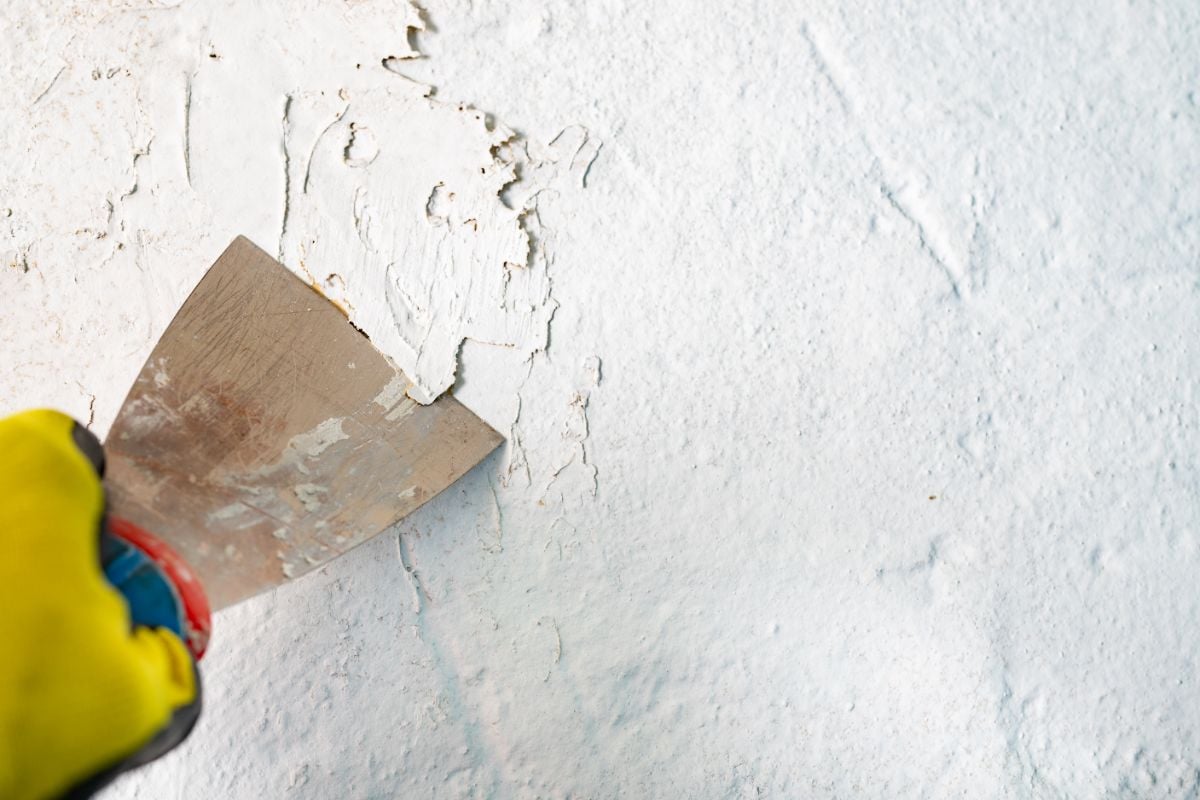 Una persona retira la pintura dañada utilizando un cuchillo de masilla.