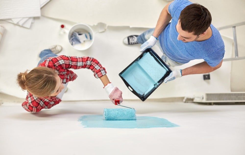 Una pareja pintando pintura plana sobre la pintura cáscara de huevo de su pared.