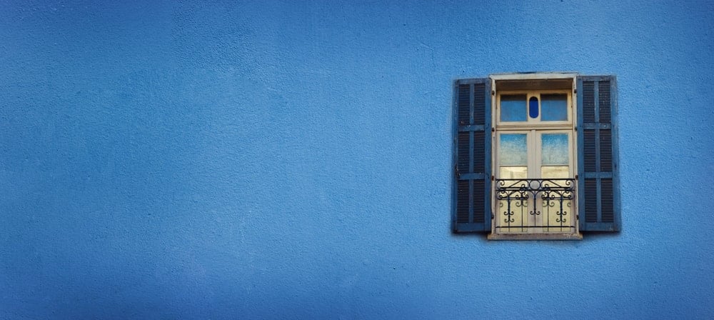 Esta es una gran pared exterior pintada con pintura plana azul adornada con una ventana.